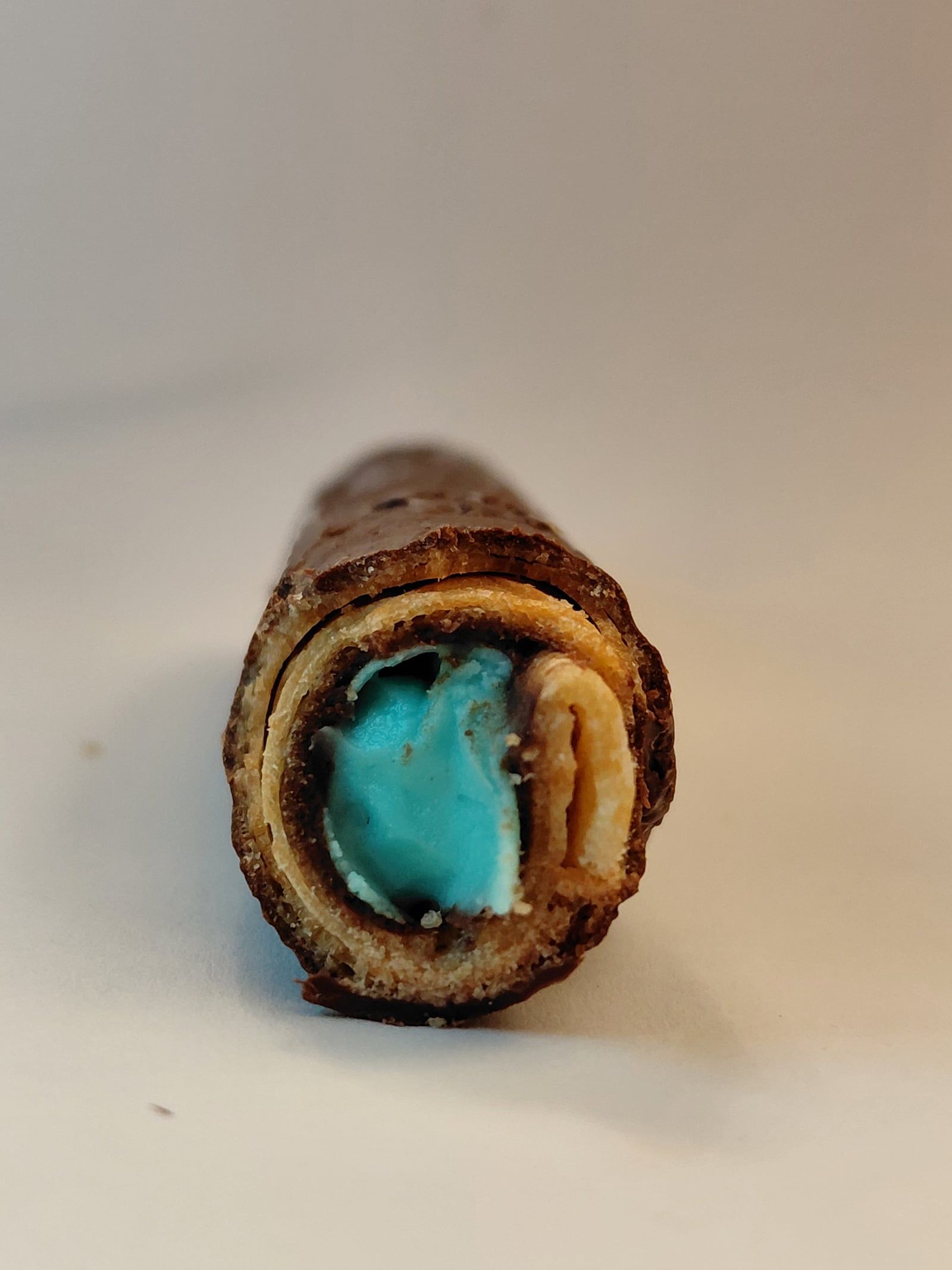 Close-up of a handmade habanito showing its crunchy rolled layers, chocolate coating and blue filling